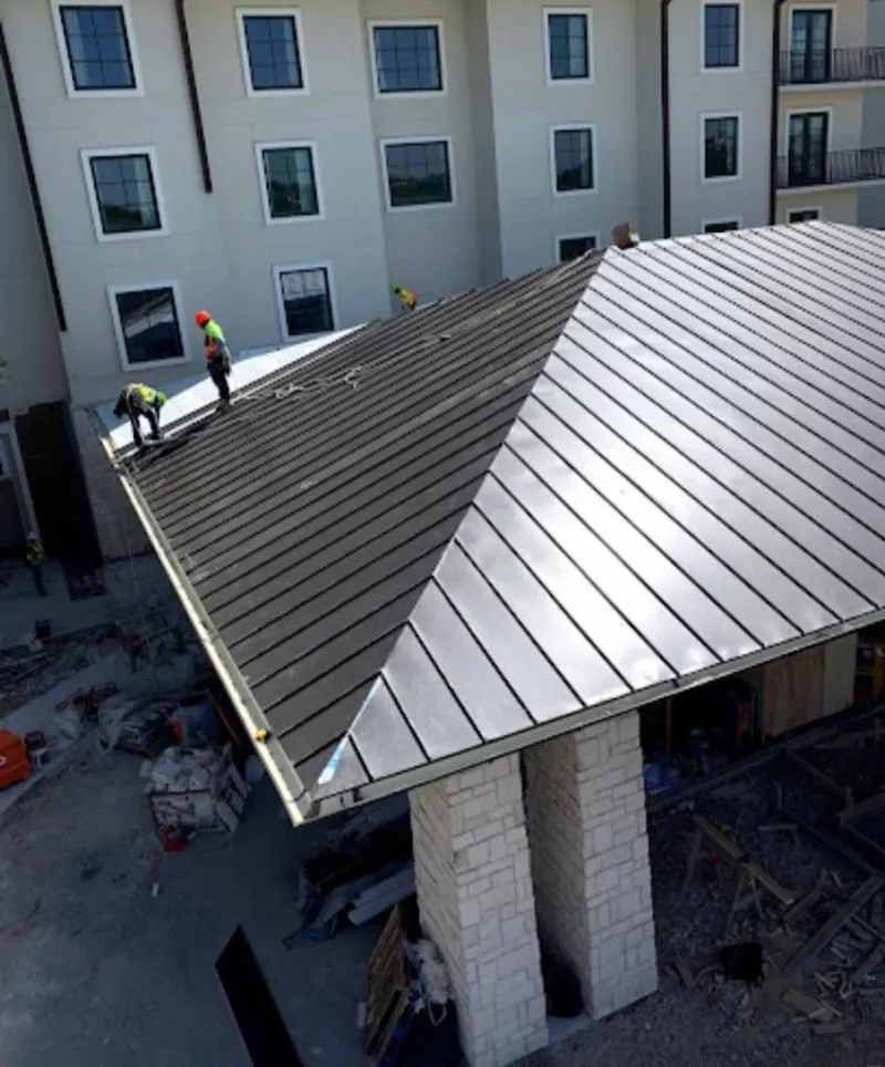 Crew installing standing seam metal roof panels on a commercial project in South Fayette